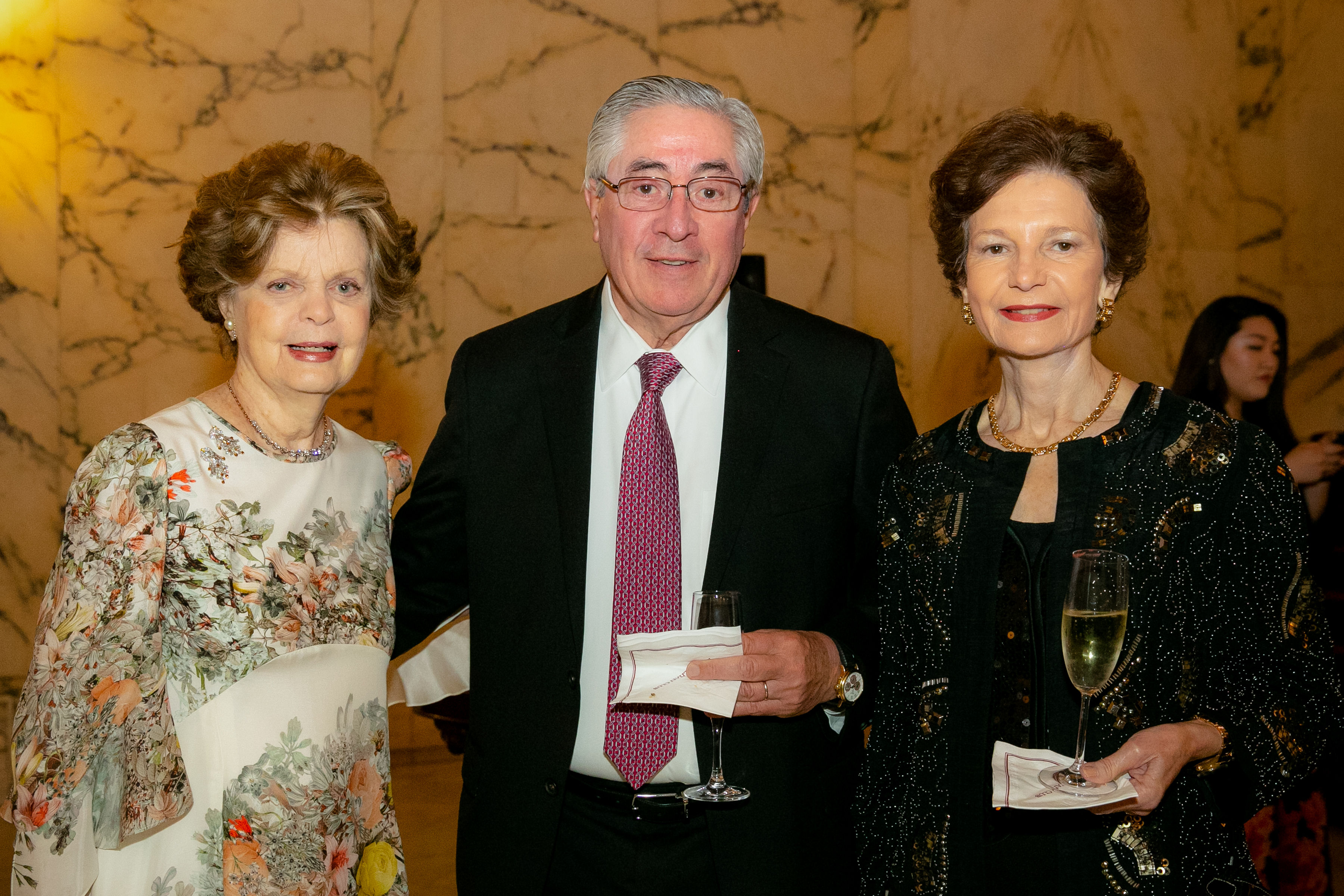Dr. Legato standing next to a male and female guest holding champagne glasses