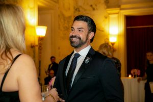A man with a beard and black suit smiles at a woman at the Gala