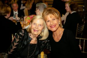 Two women seated side by side smile at the camera during 2019 Gala Event