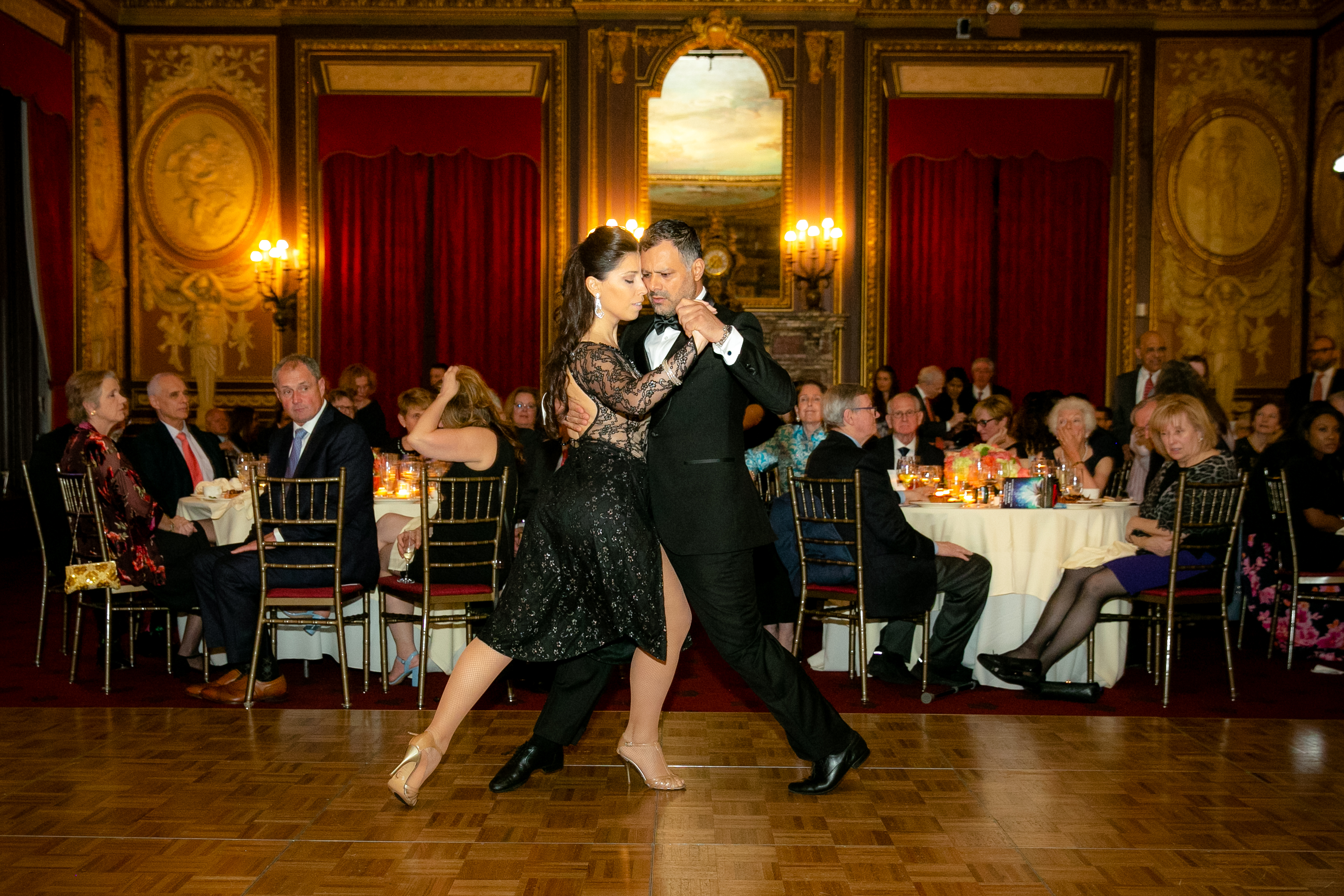 A man and a woman dance together while seated guests watch behind them