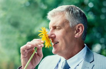 man smelling yellow flower